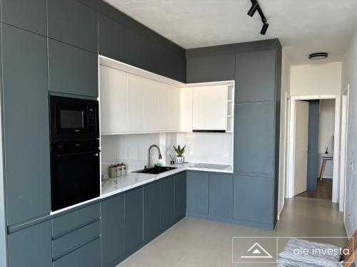a kitchen with blue and white cabinets and a sink at Green Coast 153a - by Ale Investa in Palasë