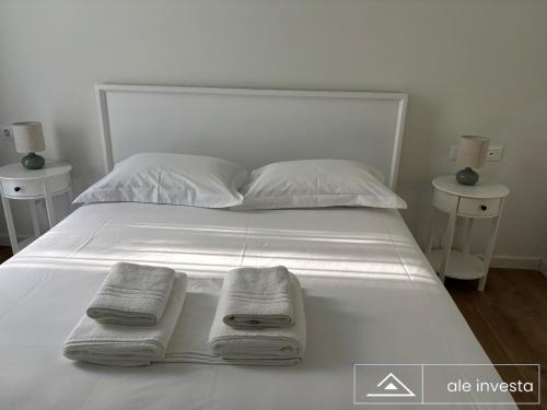 a white bed with towels on it with two night stands at Green Coast 153a - by Ale Investa in Palasë
