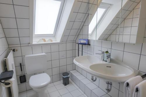 a white bathroom with a sink and a toilet at Boardinghouse in Büsum