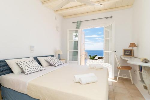 a bedroom with a large bed with a view of the ocean at Cycladic Boungainvillea Home in Kalafatis
