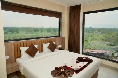 two beds in a room with a large window at Hotel Rio in Siliguri
