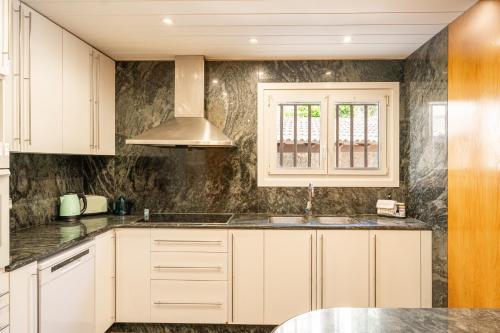 a kitchen with white cabinets and a sink at Majordoms Art in Sant Feliu de Pallerols