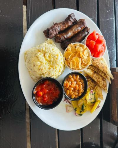 a plate of breakfast food with sausage eggs and other foods at Pine Breeze Getaway Lukenya in Athi River