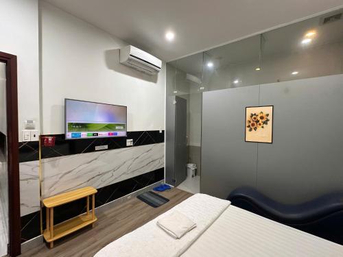 a bedroom with a bed and a tv on a wall at Khách Sạn Điểm Hẹn in Ho Chi Minh City