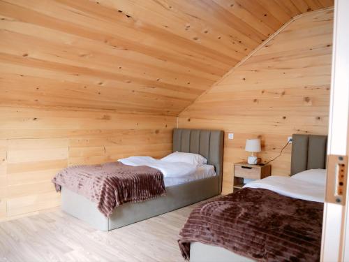 two beds in a room with a wooden ceiling at Gablile apartments in Mestia