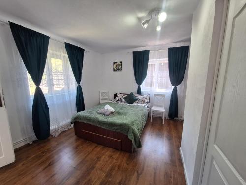 a bedroom with a bed with a green blanket at Șura Moșului in Dobîca