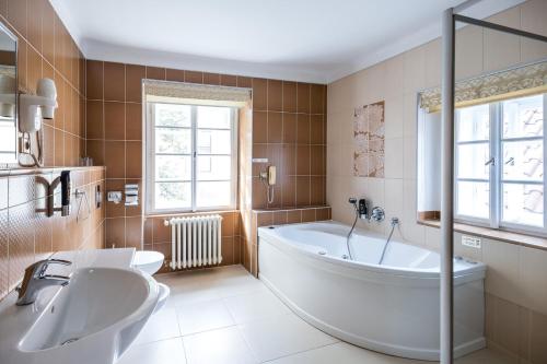 a bathroom with a large tub and two sinks at Hotel Metamorphis in Prague