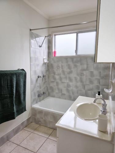 a white bathroom with a sink and a bath tub at The Pine Rest - Spacious & Central Haven in Brendale