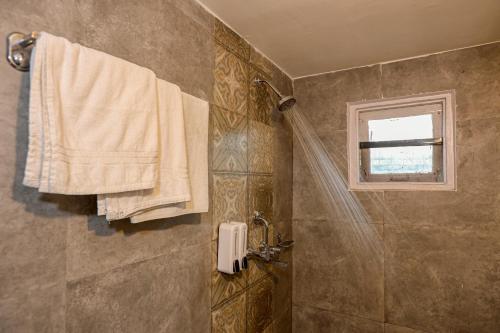 a bathroom with a shower and a window and towels at Bardibas Resort in Tulsi