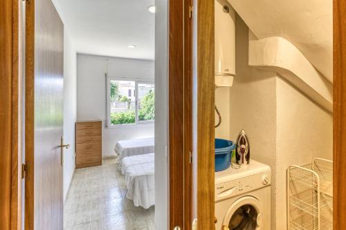 a laundry room with two beds and a hallway at Casa con piscina comunitaria in L'Escala