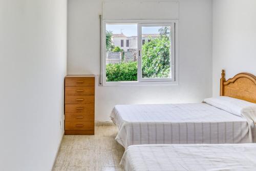 a bedroom with two beds and a window at Casa con piscina comunitaria in L'Escala