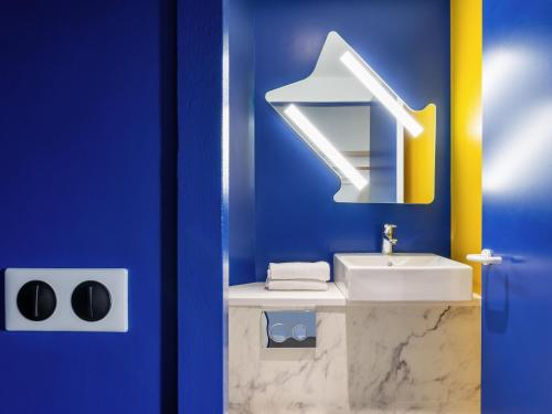 a blue bathroom with a sink and a mirror at ibis budget Lyon Est Beynost in Beynost