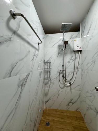 a shower in a bathroom with white marble walls at Honey Bliss Pool Villa in Hat Yai