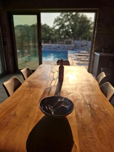 a wooden table with a bottle and glasses on it at Bellevia Stone Pool Villa in Kouvéllai