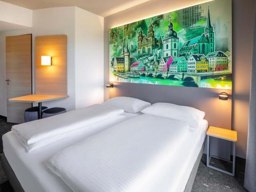 a white bed in a room with a painting on the wall at B&B HOTEL Wertheim in Wertheim