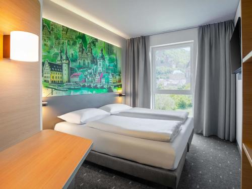a bedroom with two beds and a large window at B&B HOTEL Wertheim in Wertheim