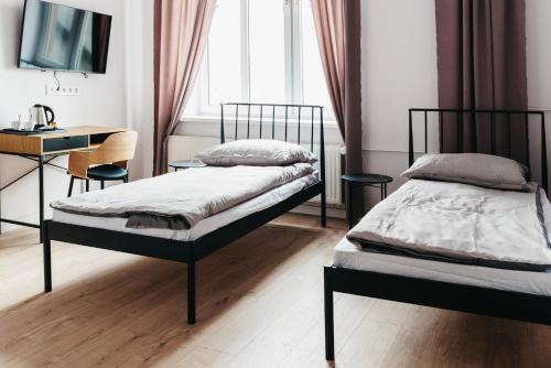 a bedroom with two beds and a desk and a table at Hostel Kamienica 9 in Sosnowiec