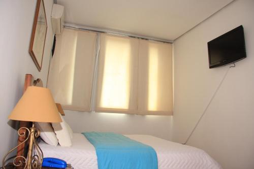 a bedroom with a bed and a window with a television at Cazuza Palace Hotel in Tupã