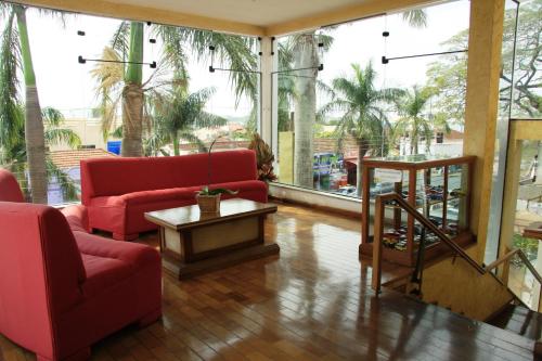 a living room with red furniture and large windows at Cazuza Palace Hotel in Tupã