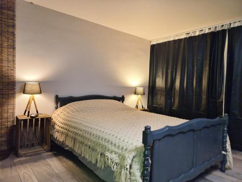 a bedroom with a bed with black curtains and two lamps at Cocoon Hébergement Wellness in Chimay