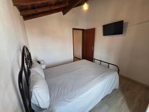 a bedroom with a white bed and a flat screen tv at Casa Centro Montargil in Montargil