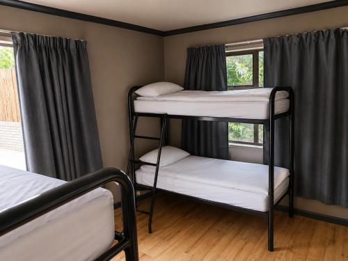 a room with three bunk beds and two windows at Lungile Backpackers in Gqeberha