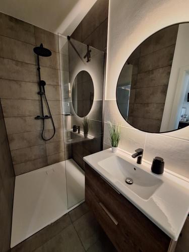 a bathroom with a sink and a shower and a mirror at Ferienwohnung III in Eisenhüttenstadt