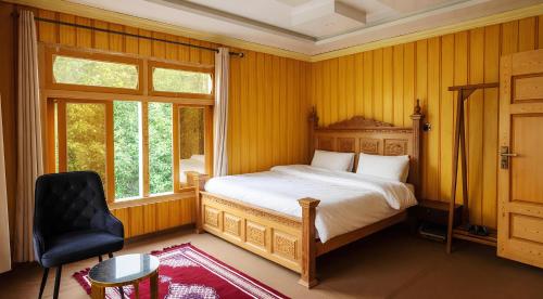 a bedroom with a bed and a chair and a window at Alpine Resort Khaplu in Khaplu
