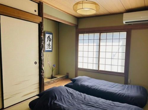 a room with two beds and a large window at Hirakata house, Easy Access to Kyoto and Osaka in Hirakata
