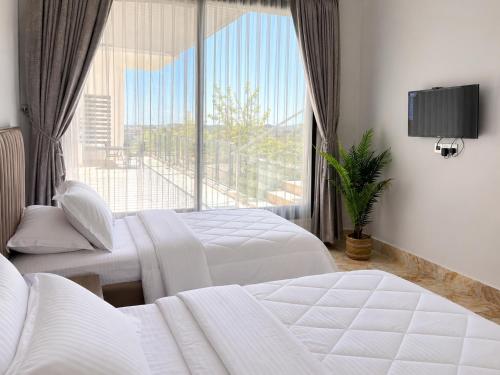 a bedroom with two beds and a large window at Zahret Al Roman in Sayq
