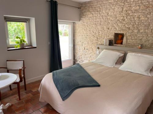 a bedroom with a large bed with a brick wall at La chambre des clefs in Ranville
