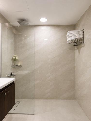 a bathroom with a shower with a glass door at Lancaster Hotel Apartments-Gardens in Amman