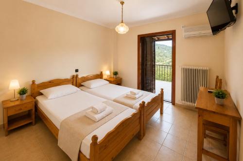 a bedroom with two beds and a television and a balcony at Panorama Plataria Ionio Studios&Apartments in Plataria