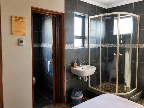 a bathroom with a shower and a sink at Lungile Backpackers in Gqeberha
