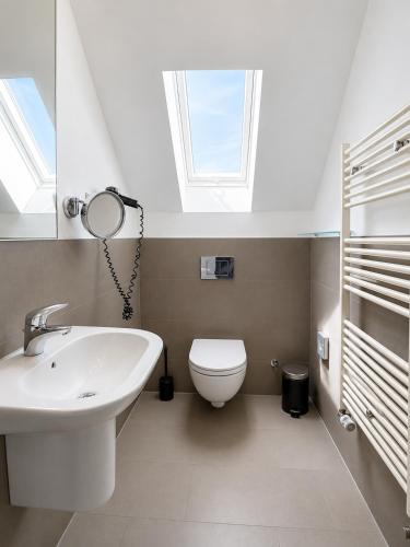 a bathroom with a sink and a toilet with a skylight at Elion Hotel Siegen in Siegen
