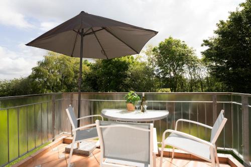 a patio with a table and chairs and an umbrella at Meerzeit Fehmarn in Wulfen auf Fehmarn