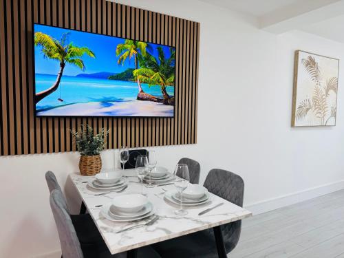 a dining room with a table with a tv on the wall at Deluxe One-Bedroom Apartment, Central in Swindon