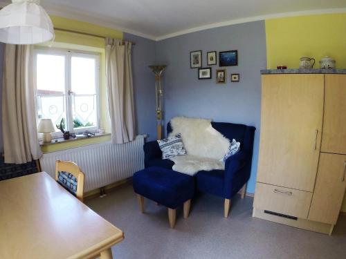 a living room with a blue chair and a window at Ferienwohnung Ulrike in Steingaden