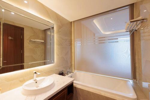 a bathroom with a sink and a mirror and a tub at Oyster Bay Vũng Tàu - Seaside Pool Escape in Vung Tau