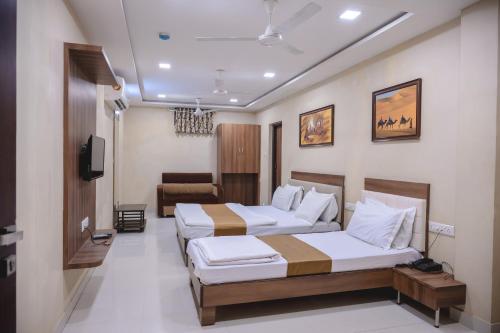 a hotel room with two beds and a couch at StayGuru Park View Residency in Bhuj