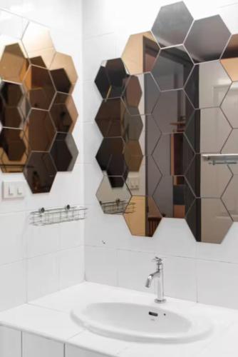 a bathroom with a sink and two mirrors on the wall at Bangkok Prime Location Residence in Makkasan