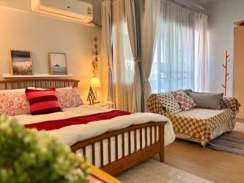 a bedroom with a bed and a couch and a window at Bangkok Prime Location Residence in Makkasan