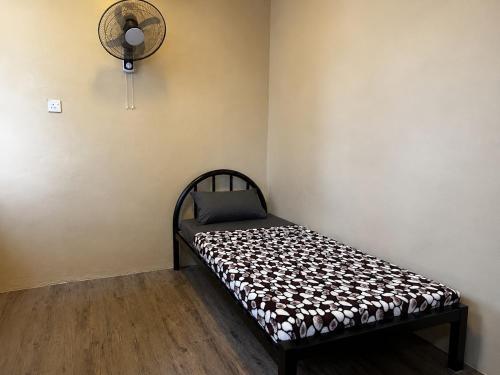 a bed in a room with a fan on the wall at Ghazrins Garuda Hotel in Johor Bahru