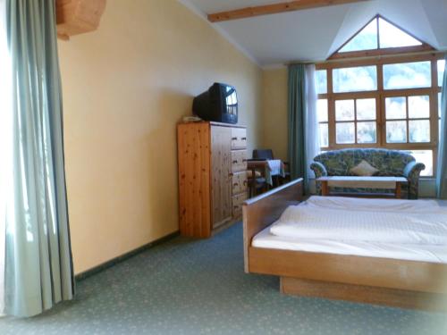 Schlafzimmer mit einem Bett, einem TV und einem Fenster in der Unterkunft Pension Grünauhof in Grünau im Almtal