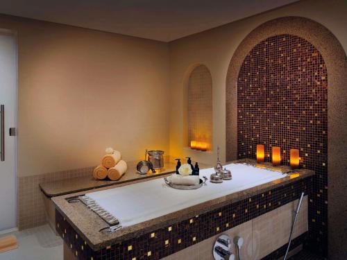 a bathroom with a bath tub with a sink at Mövenpick Hotel Bahrain in Manama