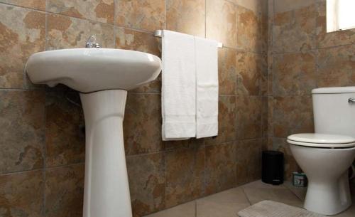 a bathroom with a sink and a toilet and towels at Tubalala Properties in Rustenburg