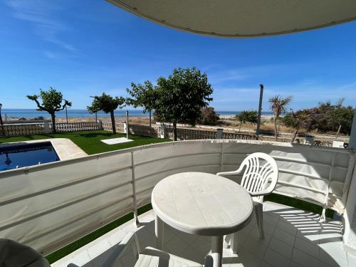 a white table and chair on a balcony with the ocean at Right on the beach in Cubelles