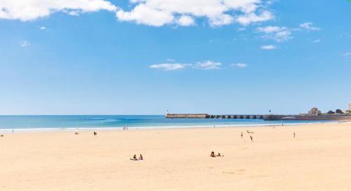 a group of people on a beach near the ocean at L'Escale Sablaise in Les Sables-d'Olonne