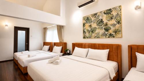 two beds in a room with white walls at Bungalow Perkasa in Kuala Lumpur