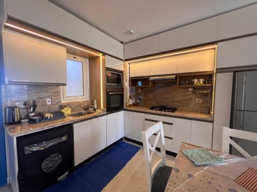 a kitchen with white cabinets and a table and a dining room at MV Ras El Hakma 190 A in Ras Elhekma